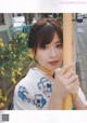 A woman in a kimono leaning against a pole.