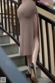 A woman in a brown dress is standing on some stairs.