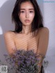 A naked woman holding a bunch of lavender flowers.