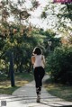 A woman jogging down a sidewalk in a park.