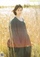 A woman standing in a field of tall grass.