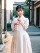 A woman in a white and pink hanbok is posing for a picture.