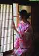 A woman in a pink kimono sitting by a window.