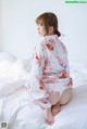 A woman sitting on top of a bed in a white robe.