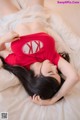 A woman laying on a bed wearing a red shirt.