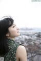 A woman in a green dress looking out over a city.