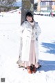 A woman standing next to a tree in the snow.