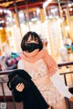 A woman wearing a face mask standing in front of a carousel.