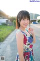 A woman in a colorful dress standing on the side of a road.