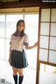 A woman in a school uniform standing by a window.