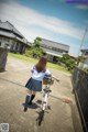 A woman in a school uniform riding a bike down a street.