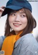 A woman wearing a baseball cap and a scarf.