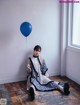 A woman sitting on the floor holding a blue balloon.