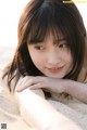 A young woman laying in the sand on a beach.