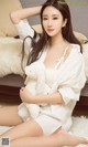 A woman sitting on a bed holding a teddy bear.