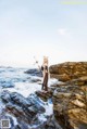 A woman standing on a rocky beach next to the ocean.