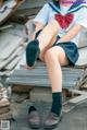 A woman in a school uniform sitting on a pile of books.