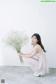 A woman kneeling down holding a bunch of baby's breath.