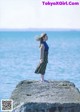 A woman standing on a rock by the ocean.