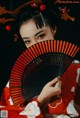 A woman in a red kimono holding a black and red fan.